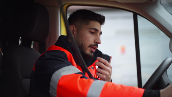 Video of young man doctor sitting and talking in to walkie-talkie in ambulance car.