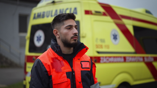 Video of a young man doctor standing in front of ambulance car.