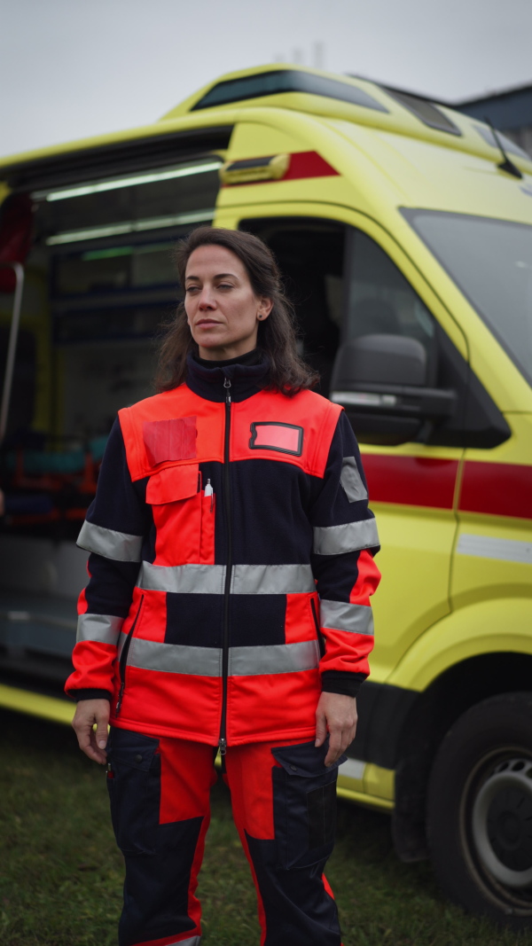 Vertical video of a young woman doctor standing in front of ambulance car.