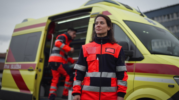 Slowmotion video of a young woman doctor standing in front of ambulance car.