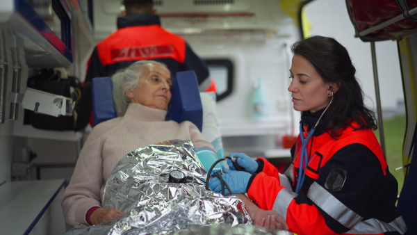 Rescuers taking care of a patient, preparing her for transport.