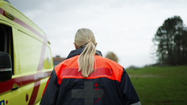 Young woman rescuer getting into the ambulance car.