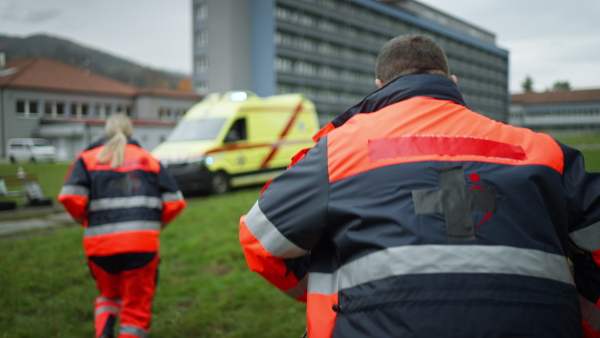 Rear view of rescuers getting in to ambulance car, preparing for a rescue operation.