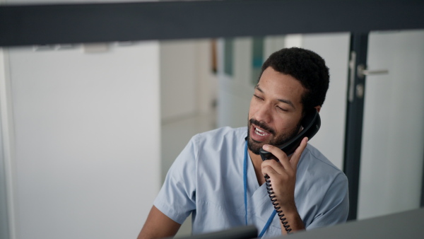 Young multiracial doctor sitting in his office and calling.