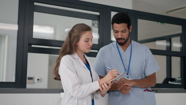 Young doctor talking with her colleague at hospital reception.