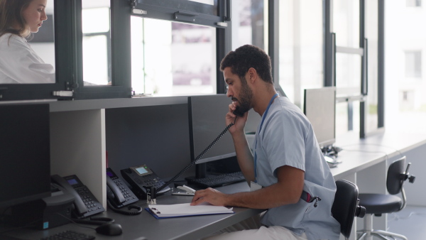 Young multiracial doctor sitting in his office and calling.