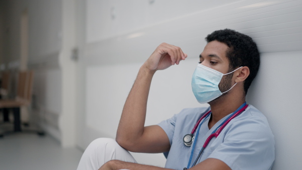 High angle view of tired doctor, sitting at a hospital corridor.