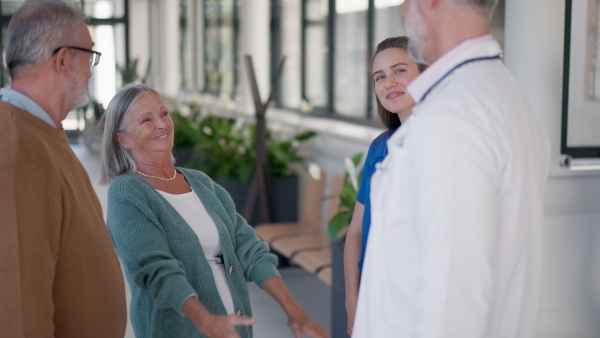 Grateful senior woman shaking hand with doctor in a hospital.