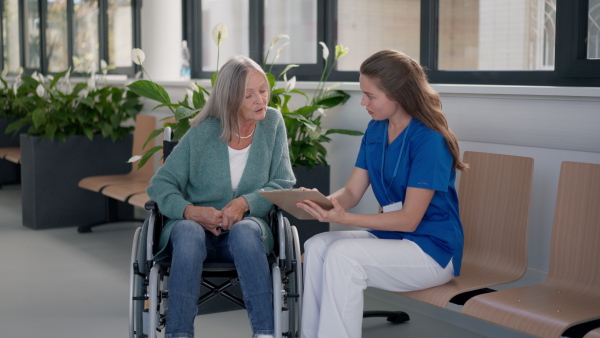 Young woman doctor taking care of senior woman at a wheelchair.