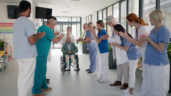 Medical staff clapping to patient who recovered from a serious illness.