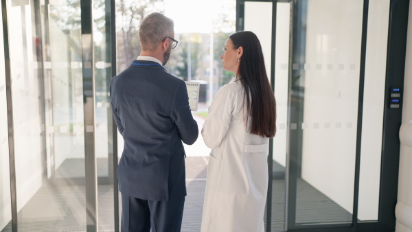 Rear view of businessman talking and explaining something to young doctor.