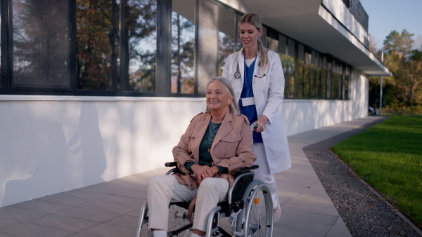 Young woman doctor taking care of senior woman at a wheelchair.