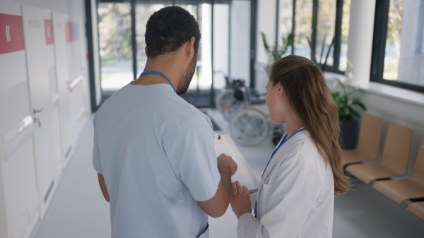 Rear view of doctors discussing something at a hospital corridor.