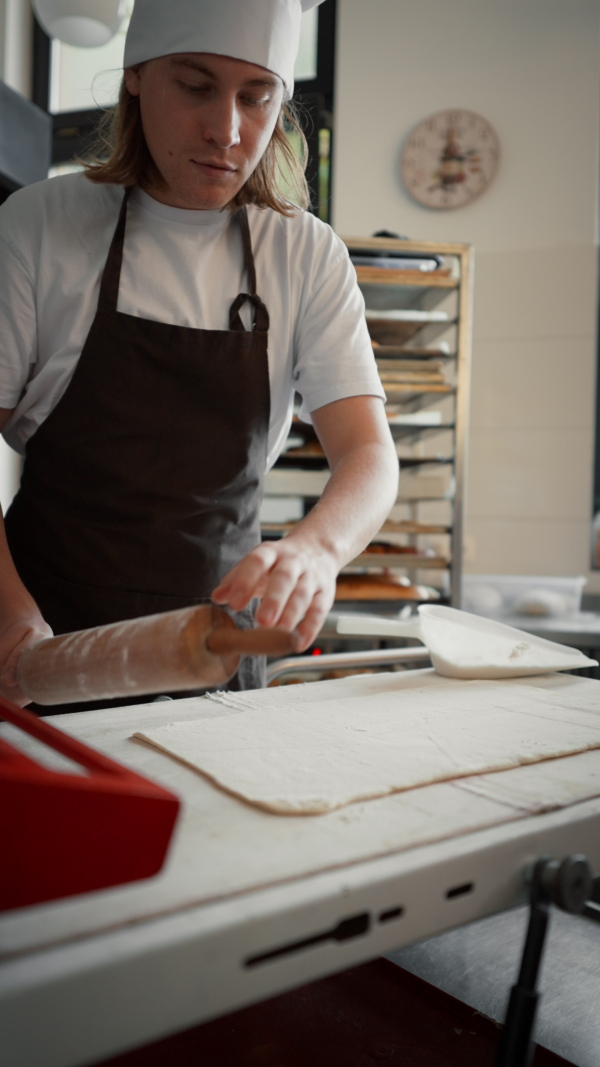 Vertical video of young baker preparing pastries in a bakery.