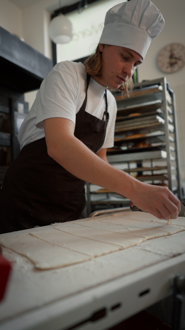 Vertical video of young baker preparing pastries in a bakery.