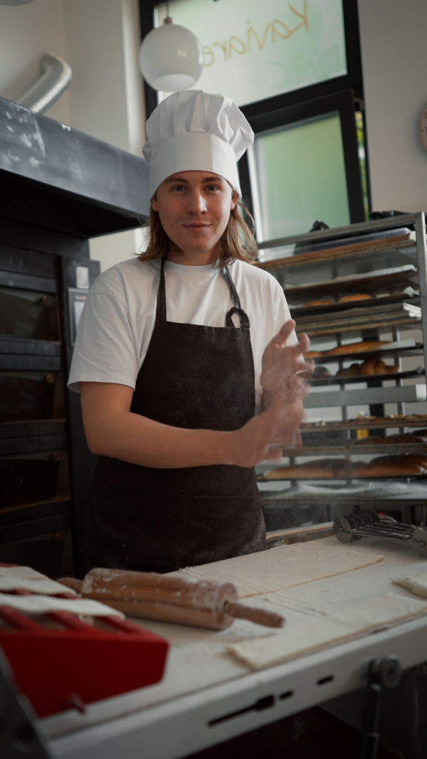 Vertical video of young baker preparing pastries in a bakery.