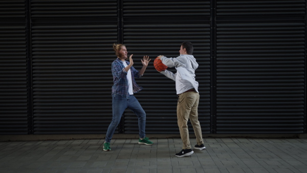 Man with down syndrome playing basketball outdoor with his friend. Concept of friendship and integration people with disability into the society.