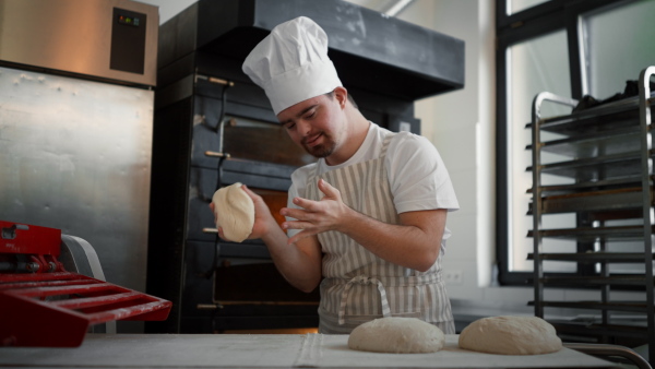 Video of a young baker with down syndrome preparing pastries in bakery. Concept of integration people with a disabilities into society.