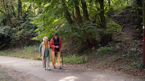 Happy senior couple in autumn clothes walking in park together.