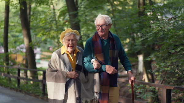 Happy senior couple in autumn clothes walking in park together.