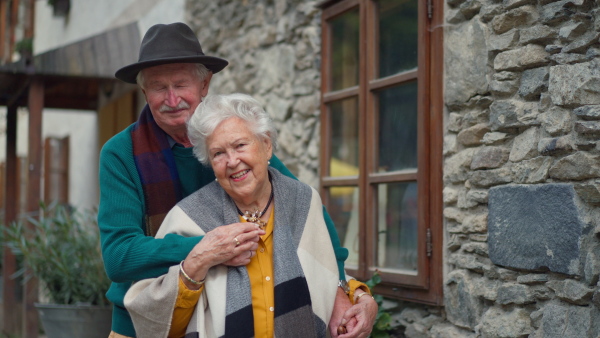 Happy senior couple posing near their old countryside house.