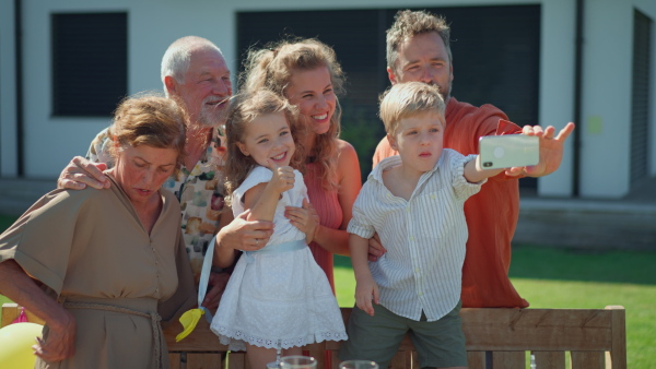 A multi generation family taking selfie on backyard in summer during garden party