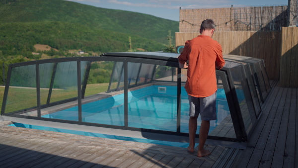 Man pushing away the pool roofing, prepairing for swimming.