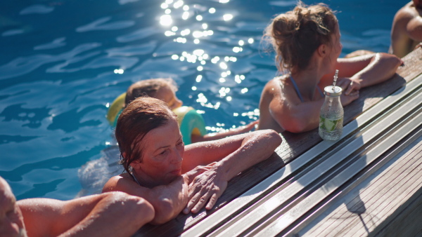 A multi generation family having fun and enjoying swimming in backyard pool.