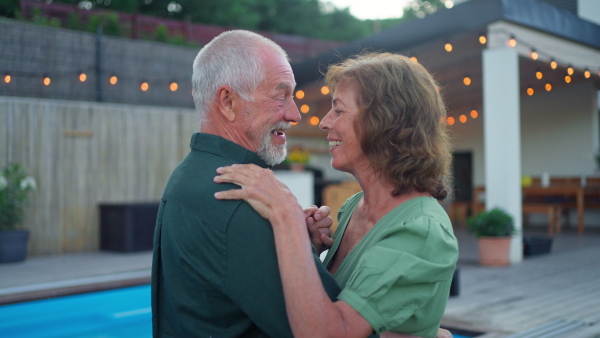 A senior woman nad man dancing together in a garden in summer