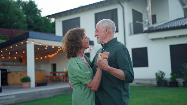 A senior woman nad man dancing together in a garden in summer