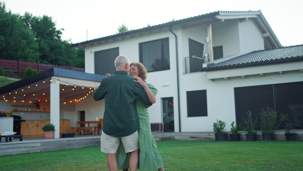 A senior woman nad man dancing together in a garden in summer