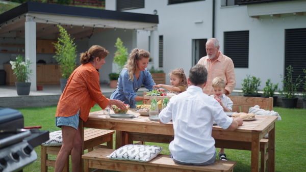 A family having garden party celebration, children are eating snacks, laughing and having fun.