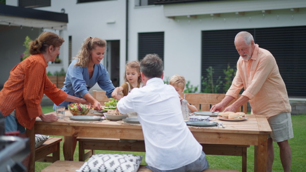 A family having garden party celebration, children are eating snacks, laughing and having fun.