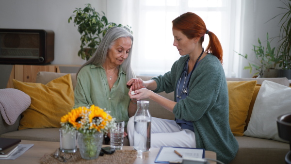 Nurse giving pills to senior woman in her home.