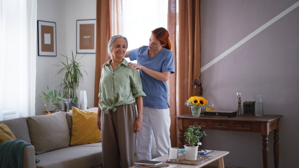 Nurse exercising with senior woman at her home, concept of a healthcare and rehabilitation.