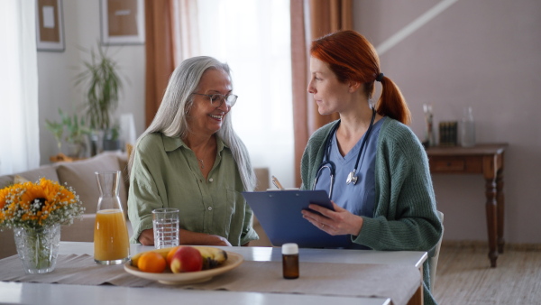 Nurse cosulting with senior woman her health condition at her home.