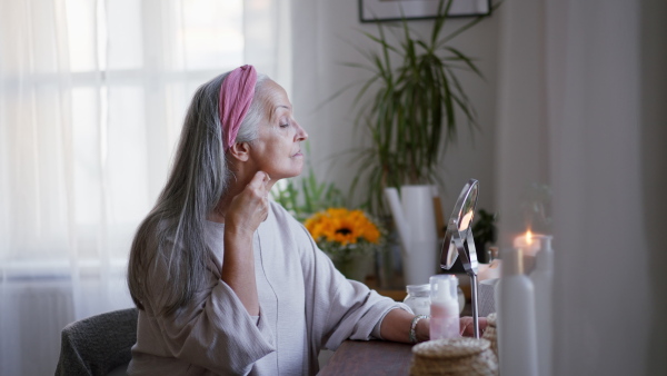 Senior woman making make up herself in home.