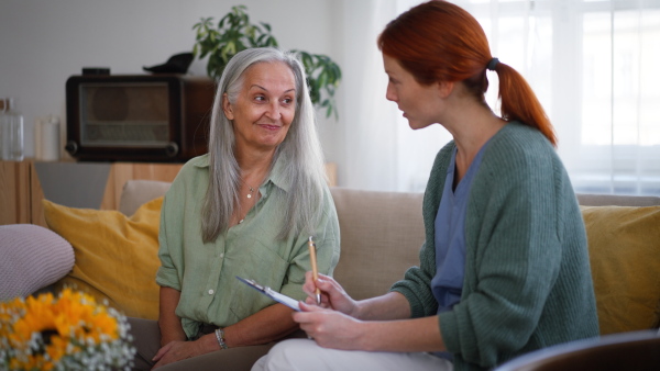 Nurse cosulting with senior woman her health condition at her home.