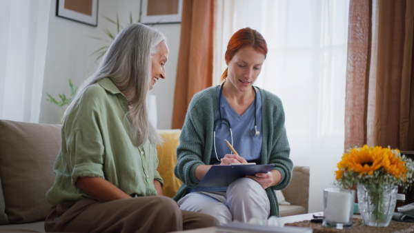 Nurse cosulting with senior woman her health condition at her home.