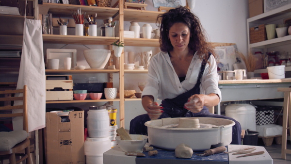 Young femalepotter working on potters wheel in workshop.