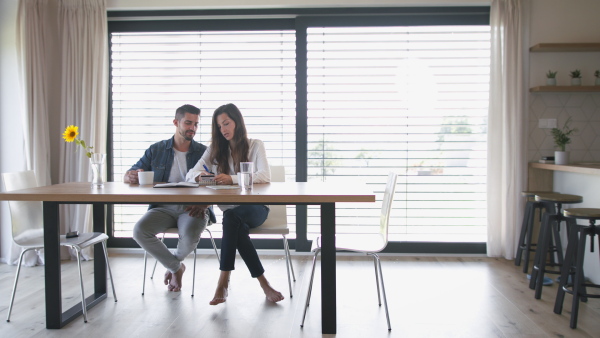 Young couple at home, planning finances, writing notes and using credit card.