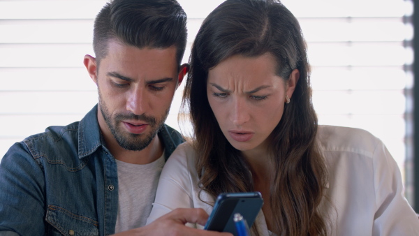 Woman and man talking about finances using mobile phone. Close up.