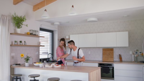 Young couple at new home, dancing and having fun while preparing breakfast.