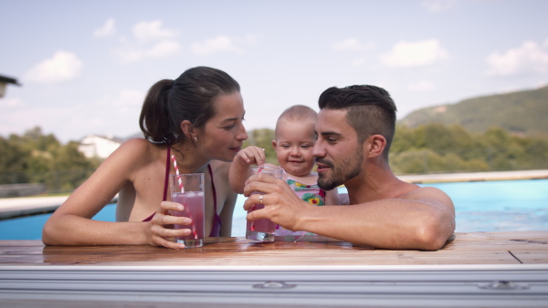 Family with baby in garden swimming pool having a fresh lemonade drink.