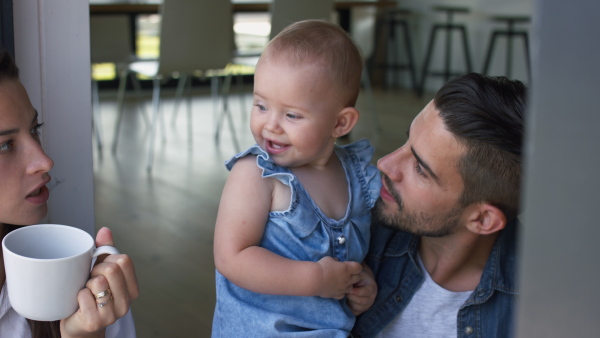 Happy baby girl smiling with parents, father kissing her.