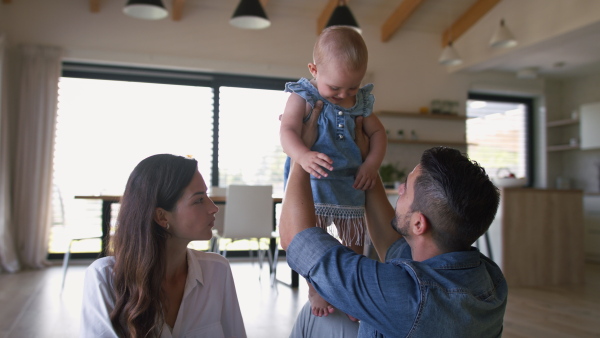 Young parents playing with toddler girl daughter at home.