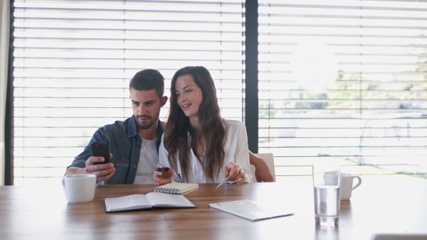 Young couple talking about finances using mobile phone and credit card.