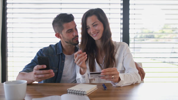 Young couple talking about finances using mobile phone application.