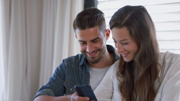 Young couple talking about finances using mobile phone at home. Close up.