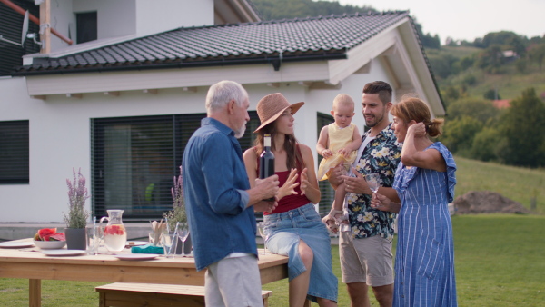 Three generations of family having a summer garden party gathering, modern house in background.